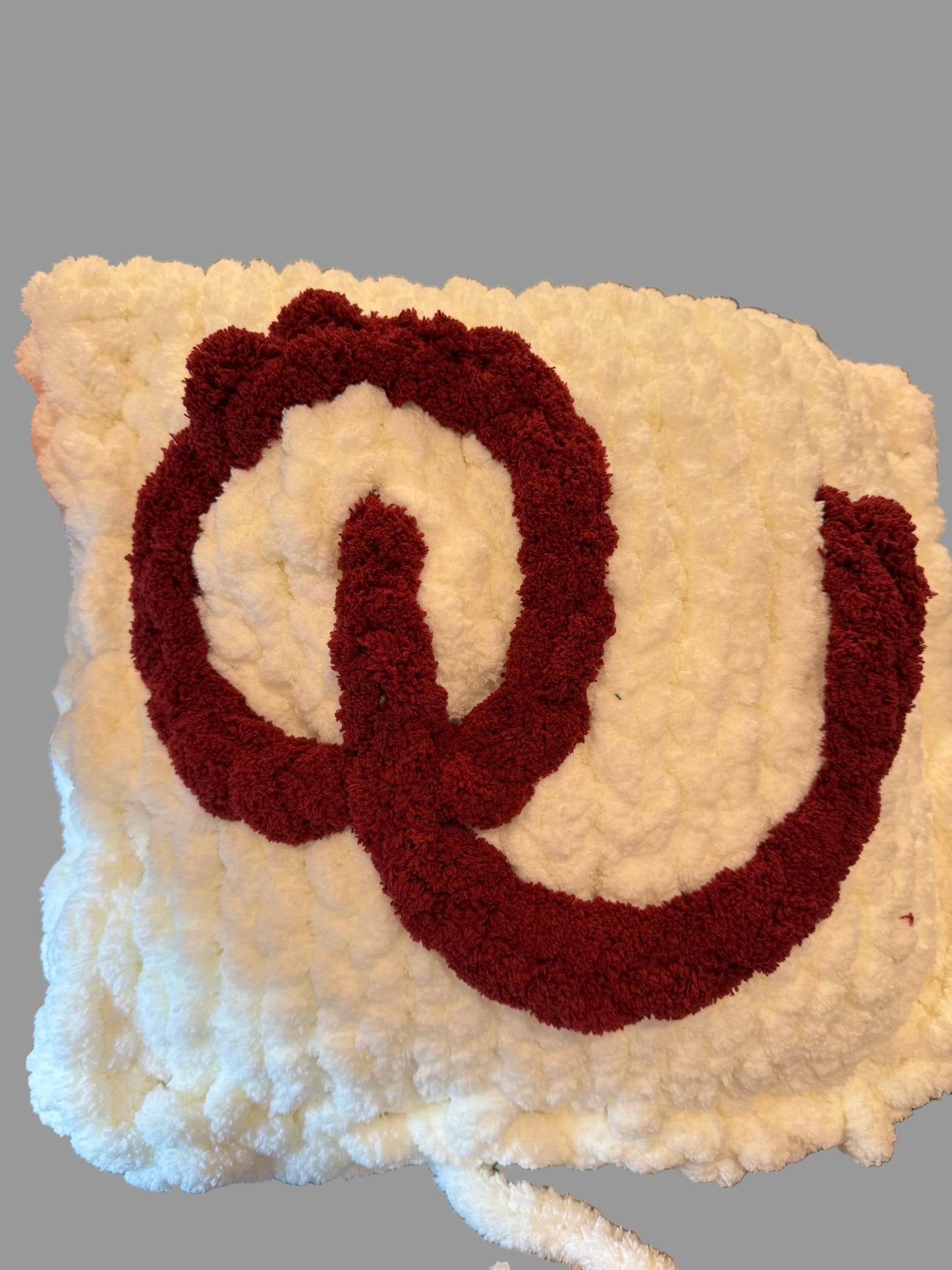 White and brown textured square with a spiral pattern held by a hand.